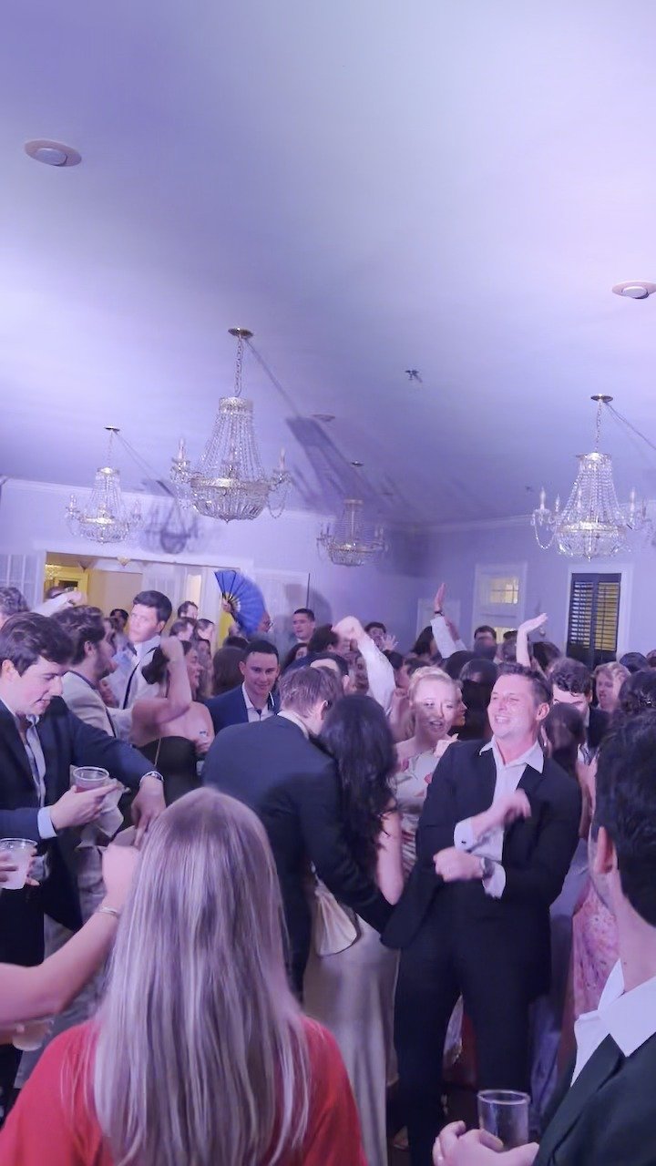 A packed wedding dance floor under chandeliers